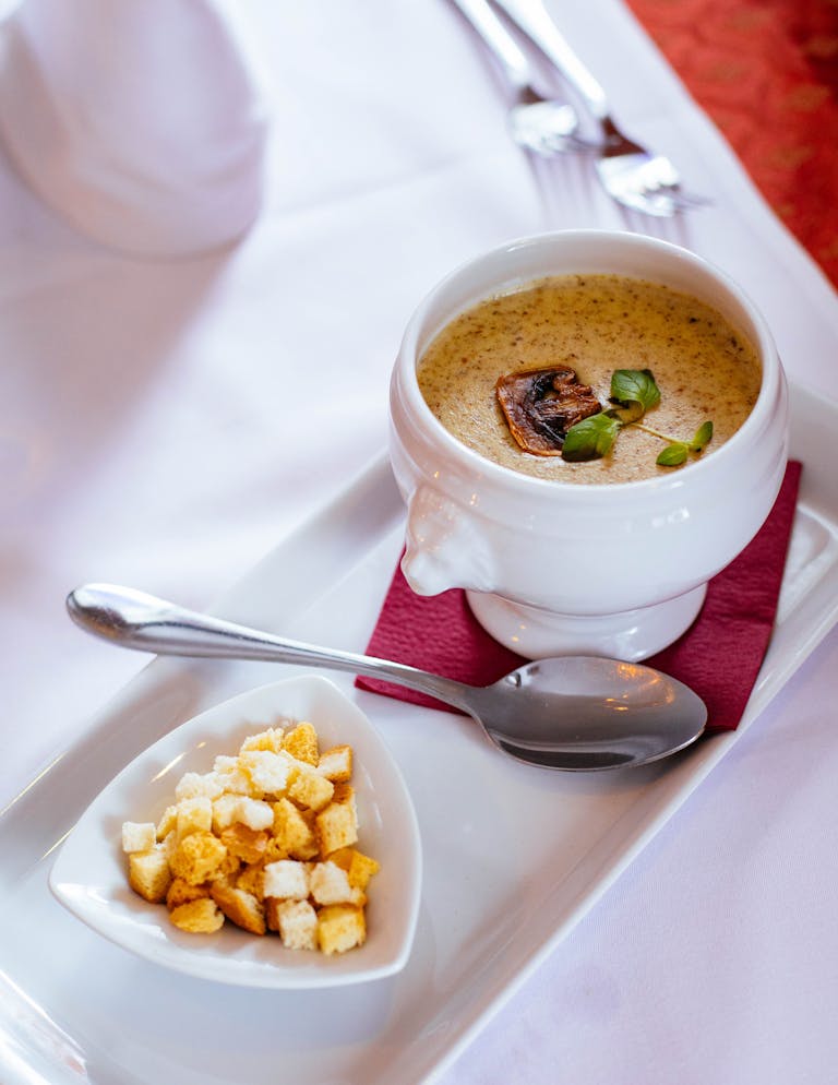 A delicious bowl of creamy mushroom soup garnished with croutons, perfect for lunch or dinner.